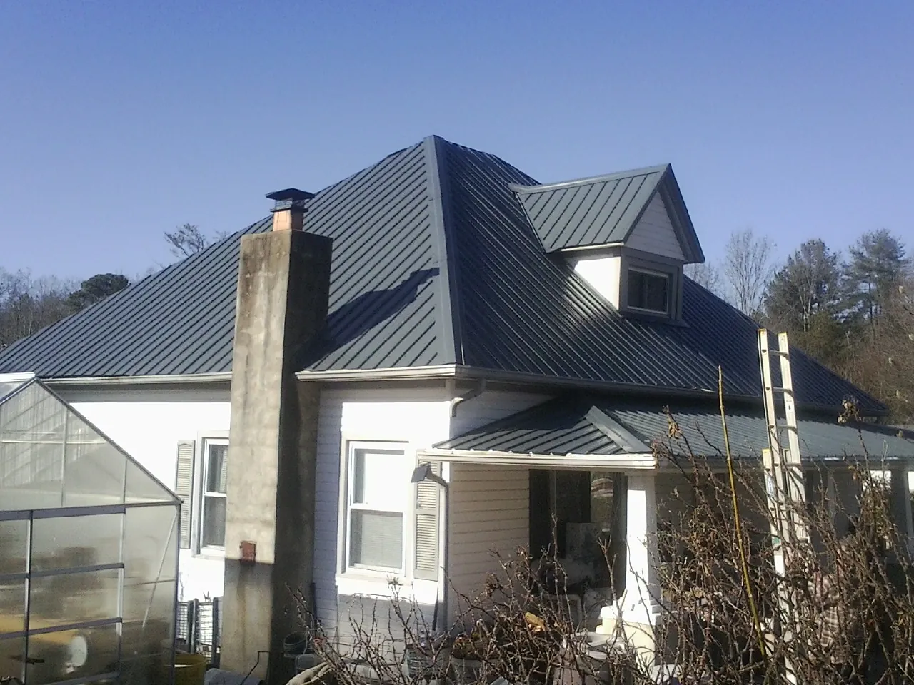 Dark blue standing seam metal roof on a white farmhouse with dormer — Slate & Tile Roof Repair by Roofing Brothers in Palenville