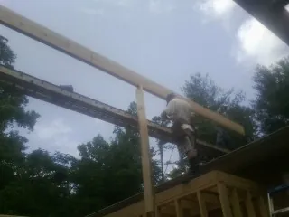 Carpenter setting a ridge beam over a new addition frame in Palenville