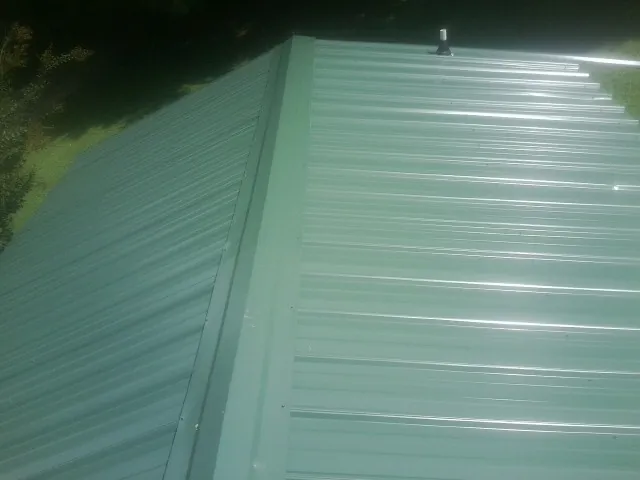 New green metal panels meeting at the ridge of a roof — Flat Roof Repair work by our crew in Palenville