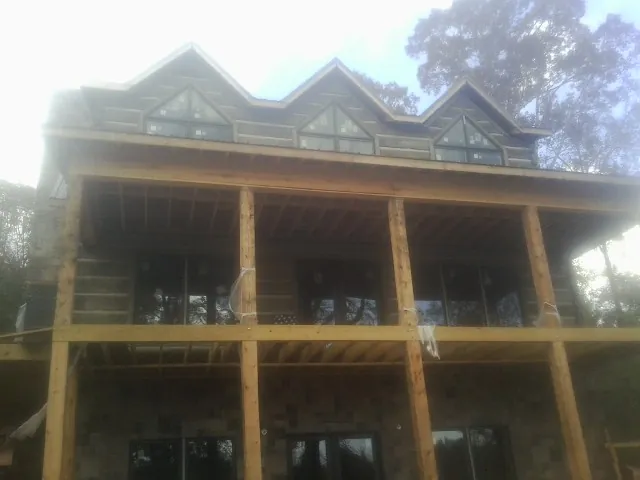 Dormers and porch framing on a large log home under construction — Roof Coating work by our crew in Palenville