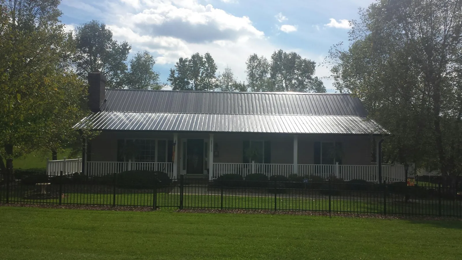 Gray metal roof on a brick ranch with a full width front porch — Gutter Guard Installation work by our crew in Palenville