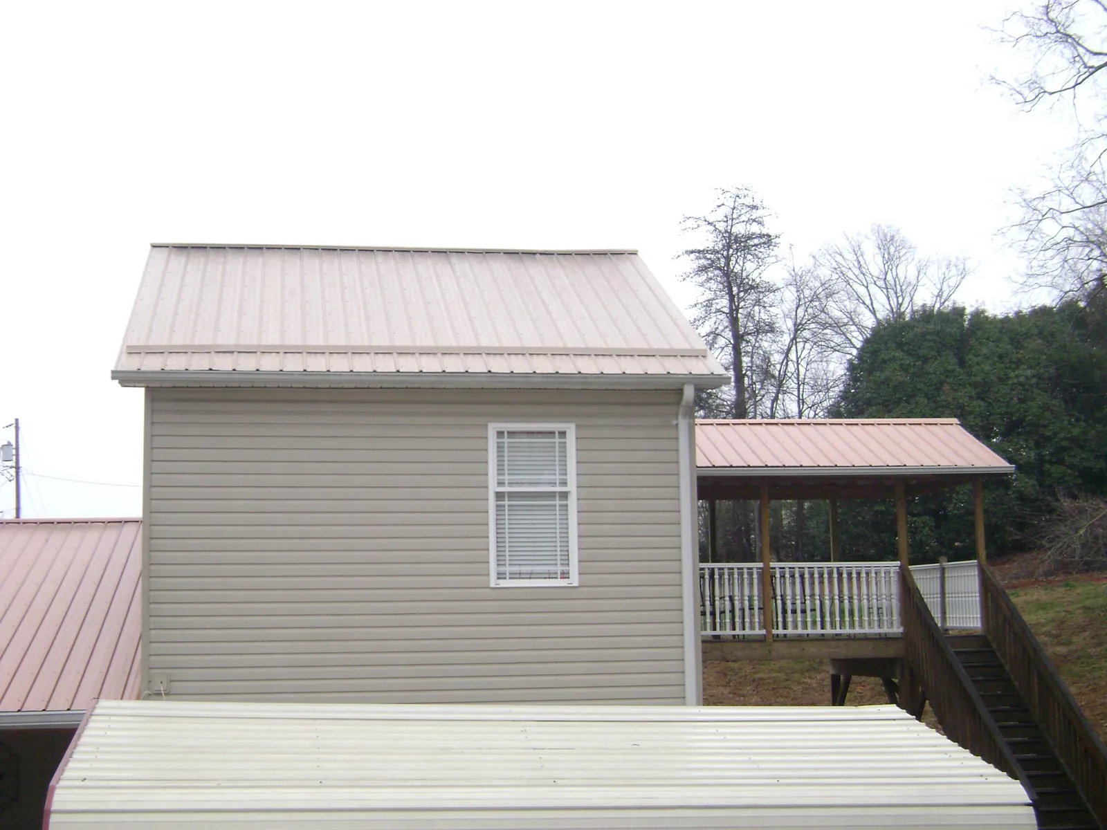 Tan metal roofs on a two story addition and attached porch, from a Roof Replacement job in Palenville