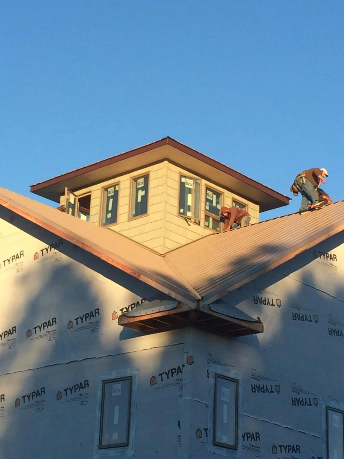 Roofers working around a rooftop cupola on a new metal roof at sunset — Roof Waterproofing in Palenville by Roofing Brothers